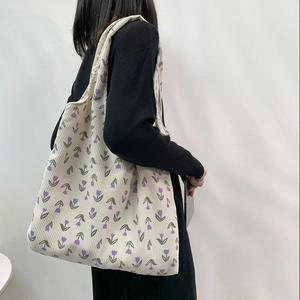 Detail of off-white corduroy tote bag with purple tulip floral print and soft texture