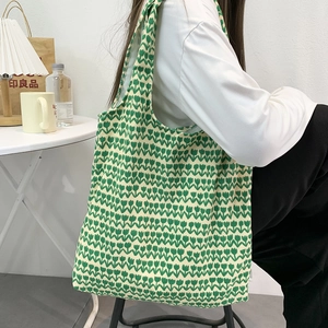 Detail view of cream canvas tote bag featuring repetitive green tulip floral patterns