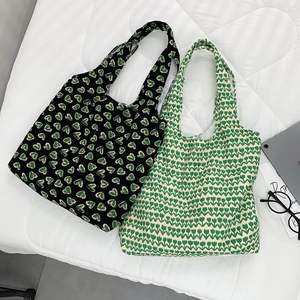 Detail of canvas tote bags featuring black green heart print and floral tulip pattern