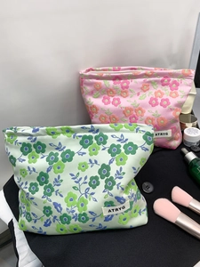 Détail de trousses de maquillage en tissu jacquard fleuri avec étiquette tissée