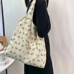 Detail showing beige corduroy tote bag with yellow tulip floral pattern on model shoulder