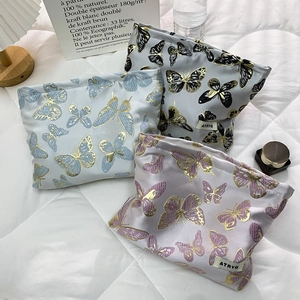 Three satin cosmetic bags with butterfly patterns and gold embroidery in aesthetic setup