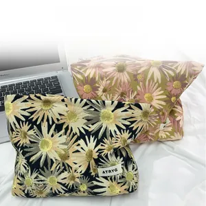 Detail of floral makeup bag with yellow daisy patterns next to a silver laptop