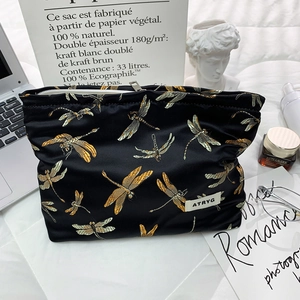 Detailed embroidery of gold dragonflies on a premium black satin luxury cosmetic bag