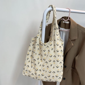 Detail of cream corduroy tote bag with yellow tulip pattern hanging on a white rack