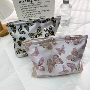 Detail of embroidered butterfly cosmetic bags with gold thread texture and zipper closure