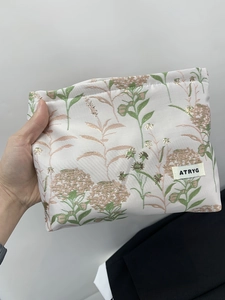 Floral fabric makeup bag with vintage hydrangea prints and brand tag held in hand