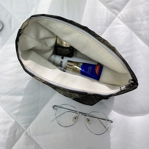 Inside view of black gold jacquard makeup bag showing spacious storage for skincare items
