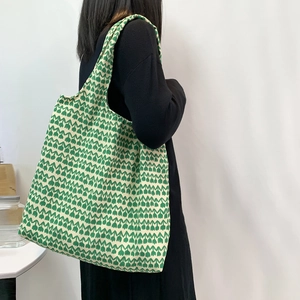Detailed view of green floral canvas tote bag with tulip patterns on female model