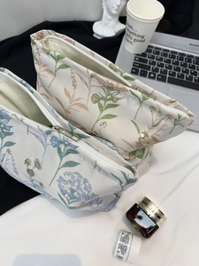Detailed view of two floral embroidered cosmetic bags with gold zippers for travel