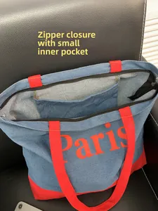Detailed interior of blue denim tote bag with red handles, zipper, and inner pocket