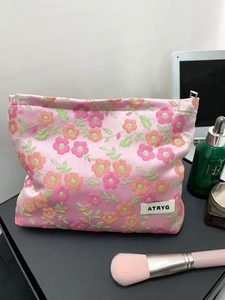 Vue détaillée d'une trousse à maquillage en jacquard rose avec motifs floraux et logo