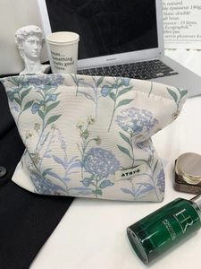 Detailed close-up of jacquard fabric with blue hydrangea patterns on a portable vanity bag