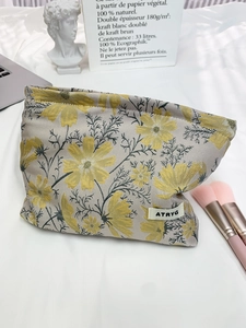 Detail of grey jacquard travel makeup bag with yellow floral patterns and ATRYG woven label