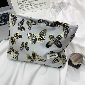 Gray butterfly embroidery makeup bag with ATRYG label on white bedding background