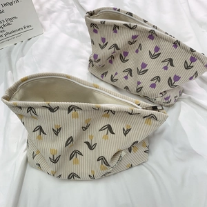 Detail of floral corduroy makeup bags with tulip prints and zipper closure on white fabric
