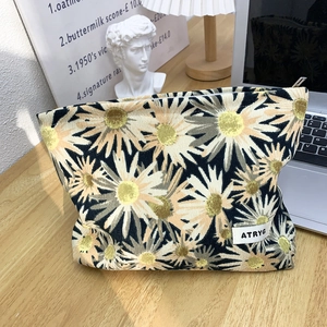 Close-up of floral makeup bag with daisy print, thick canvas texture and metal zipper