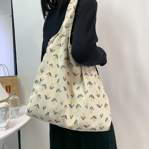Detail of corduroy tote bag with yellow tulip pattern shown on person in a clean setting