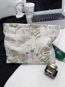 Close-up of floral jacquard embroidery on cream cosmetic bag with green plant patterns