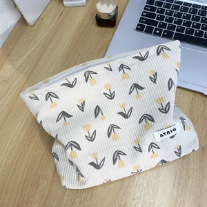 Floral corduroy cosmetic bag featuring tulip prints and a zip closure on a wooden desk