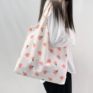 Detail of floral canvas tote bag showing pink cherry blossom patterns and shoulder strap