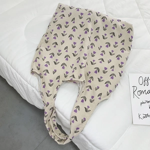 Detailed view of the purple tulip floral pattern on a beige corduroy tote bag surface
