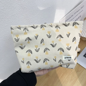 Detailed texture of floral corduroy makeup bag with tulip pattern and branded label