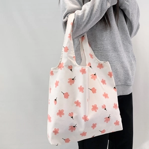 Close-up of pink cherry blossom pattern on white canvas tote bag with shoulder strap