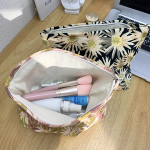 Detailed view of floral canvas makeup bags in black and pink with daisy patterns