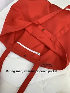 Detail of red canvas tote bag with reinforced straps, snap button, and internal zipper pocket