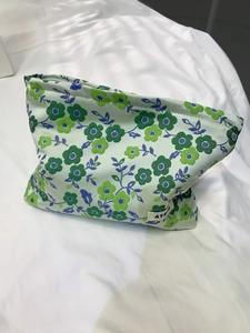 Gros plan d'une trousse à maquillage jacquard fleurie avec étiquette sur tissu blanc