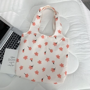 Macro view of floral canvas tote bag on white bed with laptop and book setup