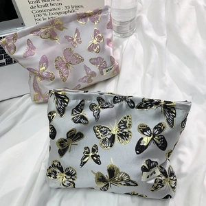 Detail of two butterfly printed travel bags with gold foil texture and zipper closure