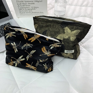 Close-up of golden dragonfly and butterfly embroidery on luxury velvet cosmetic bags