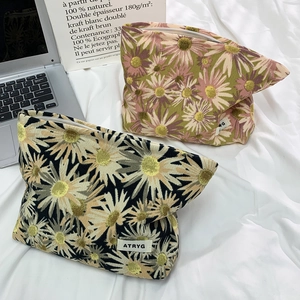 Detail of floral corduroy makeup bags with daisy patterns and metal zipper closure