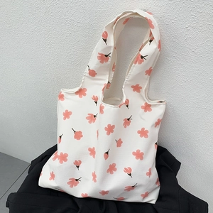 Detail of white canvas tote bag featuring fresh pink floral prints and sturdy handles