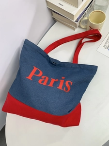 Detail of red and blue denim tote bag with Paris print on minimalist white desk