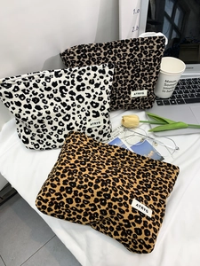 Three canvas leopard print makeup bags with zippers and ATRYG label on a white desk