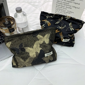 Detailed close-up of golden butterfly and dragonfly embroidery on high-capacity makeup bags