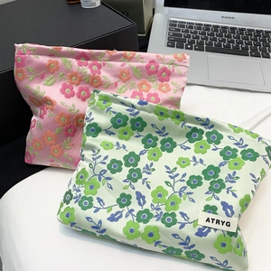 Détail des trousses de maquillage en jacquard floral rose et vert avec étiquette tissée