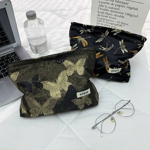 Detailed view of luxury gold butterfly and dragonfly pattern makeup bags on a desk