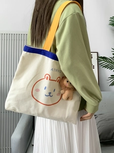 Detailansicht der beigen Canvas-Tasche mit Comic-Druck, gelben Trägern und Löwenanhänger