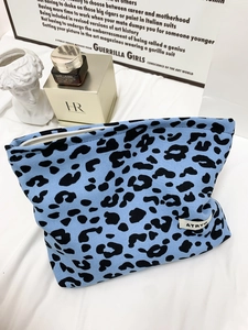 Detailed shot of blue leopard print canvas cosmetic bag with zipper on a white fabric