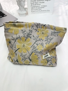 Detailed texture of the jacquard fabric makeup bag with yellow floral cosmos pattern