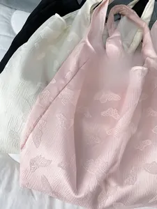 Close-up of butterfly jacquard embroidery texture on soft pink, white, and black tote bags