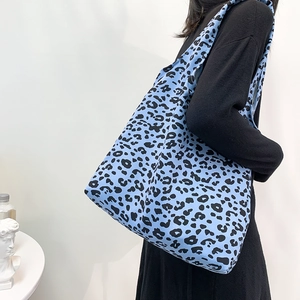 Détail du sac cabas en velours côtelé imprimé léopard bleu porté à l'épaule par un mannequin