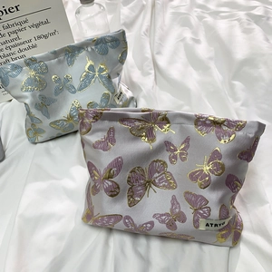 Detail of blue and purple butterfly makeup bags with gold outlines on textured fabric