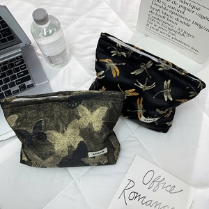 Detail of two-piece cosmetic bags with dragonfly print and golden butterfly jacquard