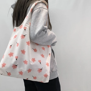 Close-up of pink cherry blossom prints on white canvas tote bag with soft texture