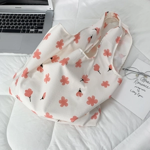 Flat lay of floral canvas tote bag with pink flowers, laptop, and books in cozy setup